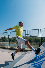 Sporty man jumping over obstacles in skatepark