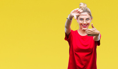 Young beautiful blonde woman wearing red t-shirt and glasses over isolated background smiling making frame with hands and fingers with happy face. Creativity and photography concept.