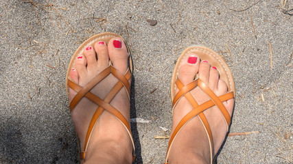 Chipped nail polish on  toes in sandals on the beach