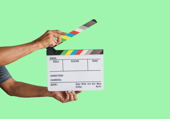 Hand holding a film clapboard slate or movie slate isolated on green background, with clipping path.
