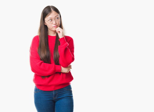 Young Chinese woman over isolated background wearing glasses with hand on chin thinking about question, pensive expression. Smiling with thoughtful face. Doubt concept.