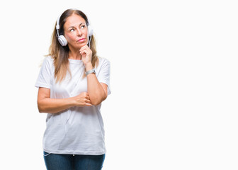 Middle age hispanic woman listening to music wearing headphones over isolated background with hand on chin thinking about question, pensive expression. Smiling with thoughtful face. Doubt concept.