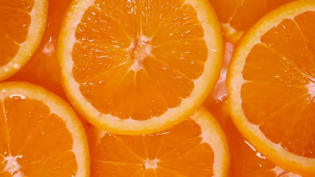 Close up sliced orange fruit falling into orange fruit piece in water background , slow motion shot