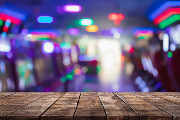 Empty wood table top on abstract blurred game center shop and nightclub lights background - can be...