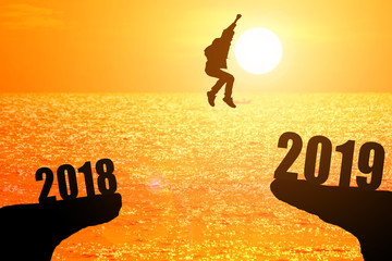 Silhouette of young man jumping between 2018 and 2019 years with beautiful sunset at the...