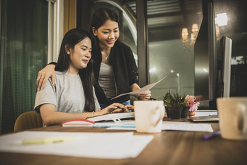 two younger asian woman freelance discussing to job on office computer