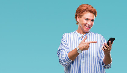 Atrractive senior caucasian redhead woman texting using smartphone over isolated background very happy pointing with hand and finger