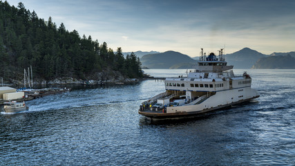 Fototapeta premium Ferry approaches the shores carrying vehicles and passengers. Beautiful British Columbia, Canada.