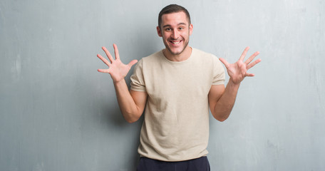 Young caucasian man over grey grunge wall very happy and excited, winner expression celebrating victory screaming with big smile and raised hands