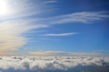 Naklejka premium Clear blue sky with white cloud in the autumn evening time. Aerial view from airplane's window. Nature background concept with copy space.