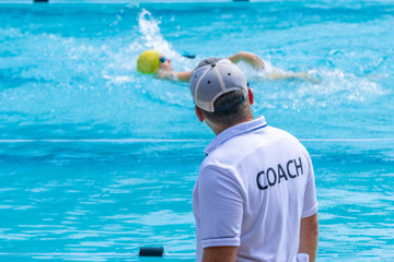 Male swimming coach watching his swimmer practice
