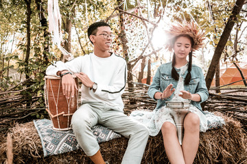 Having rest. Happy Asian man sitting near his partner while listening to music
