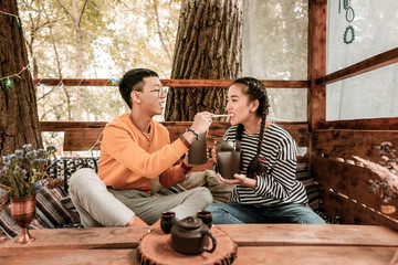 Try it. Cheerful brunette girl holding box with food while being in tree house