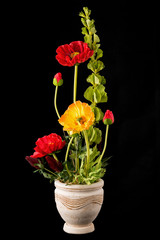 Floral arrangement from artificial poppy flowers in old ceramic flower pot.