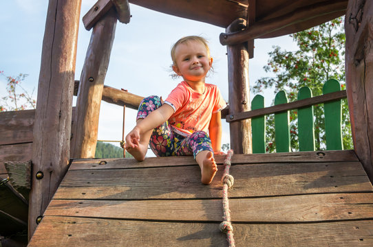 Sweet baby girl on the wooden playground for children