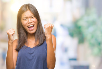 Young asian woman over isolated background very happy and excited doing winner gesture with arms raised, smiling and screaming for success. Celebration concept.