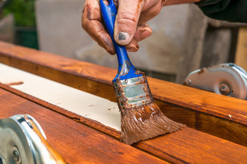 Painter with paintbrush painting wooden surface
