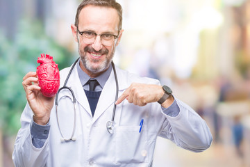 Middle age senior hoary cardiologist doctor man holding heart over isolated background with...