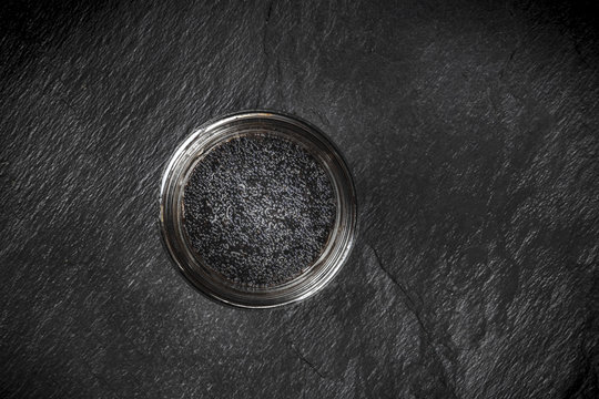 Black fish caviar in a jar, shot from the top on a black background with copyspace
