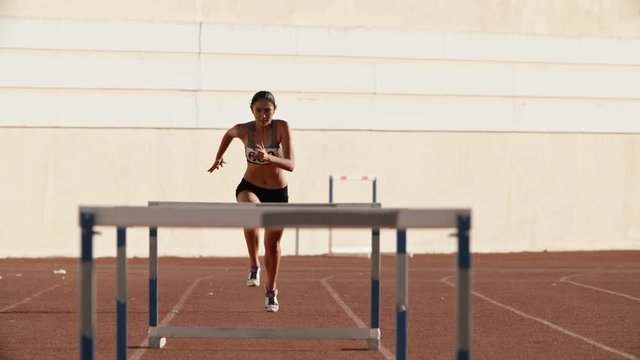 Female athlete on track. Young asian runner running on track of stadium, jumping over barriers, preparing for competition 4k