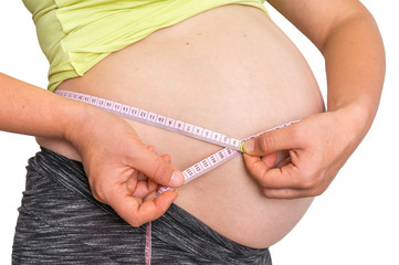Pregnant woman is measuring belly with tape meter