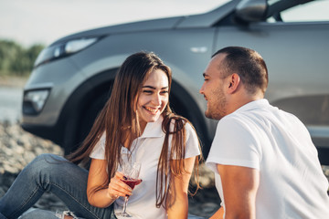 Happy Traveler Couple on Picnic into the Sunset with SUV Car