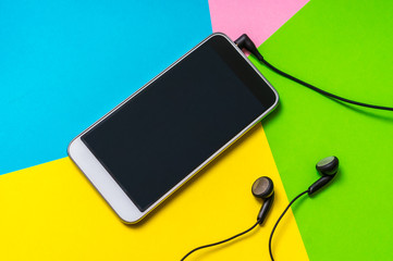 Mobile phone with headphones isolated on colorful background