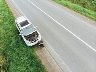 man sitting on road near broken car. trying stop car for help