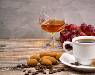 Black coffie and glass with brandy served with grape and chocolate
