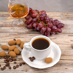Black coffie and glass with brandy served with grape and chocolate