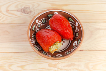 Cooked stuffed red bell peppers in a clay bowl