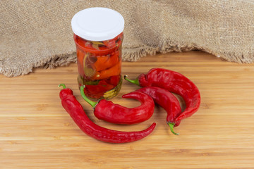 Fresh and pickled red peppers chili on a wooden surface