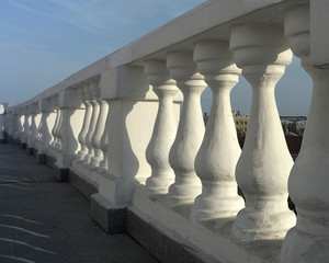 A row of white sculpted columns in the fence. An element of architecture of an Orthodox church.