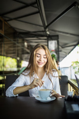 portrait of beautiful charming woman is stirring coffee in cafe and thinking