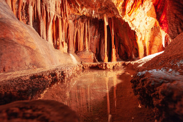 Stalactites reflecting in the water in limestone cave