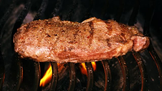 UHD of the juicy premium beef steak on a barbecue grill with flames and smok
