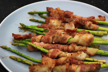 Grilled bacon wrapped green asparagus on dark background
