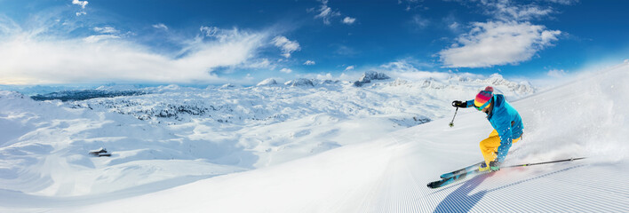 Alpine skier skiing downhill, panoramic format