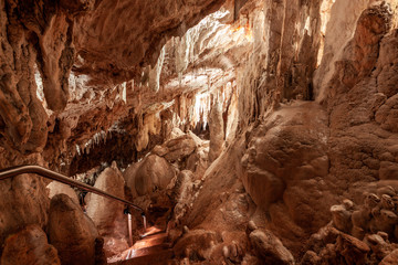Stairs leading down among stalactites and stalagmites in Glory Cave. Kosciuszko National Park, Australia