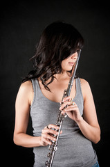 Fashion portrait in studio of beautiful young woman feeling happy with her flute against dark background in studio