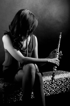 Fashion portrait in studio of beautiful young woman feeling happy with her flute against dark background in studio