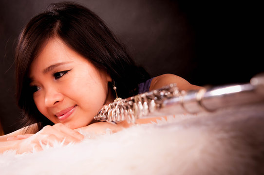 Fashion portrait in studio of beautiful young woman feeling happy with her flute against dark background in studio