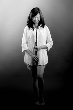 Fashion portrait in studio of beautiful young woman feeling happy with her flute against dark background in studio