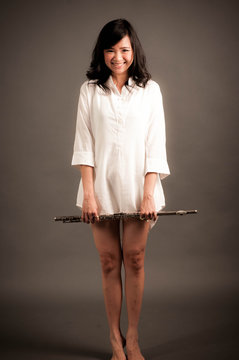 Fashion portrait in studio of beautiful young woman feeling happy with her flute against dark background in studio