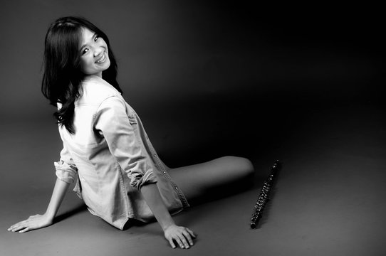 Fashion portrait in studio of beautiful young woman feeling happy with her flute against dark background in studio