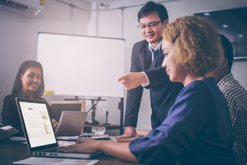 A group of employees are Asian companies and business marketing consultation meeting. The hand of the young man, pointing to the screen of the Laptop Secretary. On the graph display sales statistics.