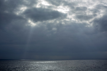 Fototapeta premium rays of light through the clouds falling on the sea