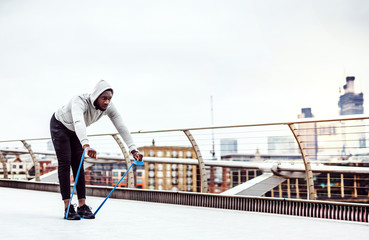Fototapeta na wymiar Young black sportsman exercising with elastic rubber bands in London.