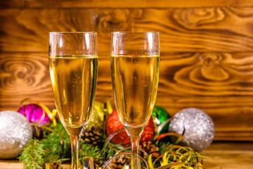 Two wineglasses with champagne and different christmas decorations on wooden table