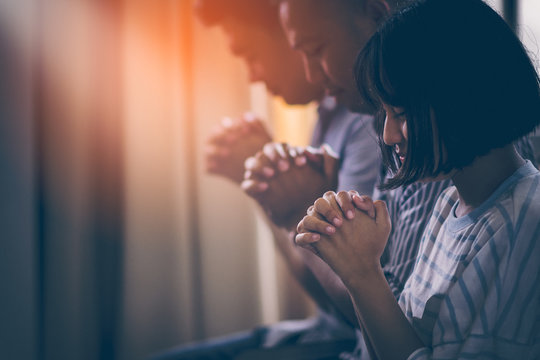 Asian Christian groups sitting within the Church Catholic. They clasped hands and closed his eyes and prayed for blessings from God. A pale sun shone in a place of worship. Everyone smiled happily.